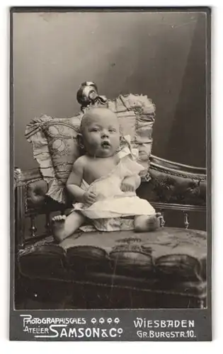 Fotografie Samson & Co., Wiesbaden, Portrait niedliches Baby im weissen Hemd mit nackigen Füssen