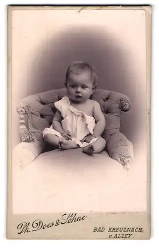Fotografie Ph. Does & Söhne, Bad Kreuznach, Portrait niedliches Kleinkind im weissen Hemd auf Sessel sitzend