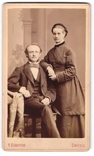 Fotografie P. Schiffer, Crefeld, Portrait bürgerliches Paar in zeitgenössischer Kleidung