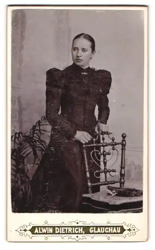 Fotografie Alwin Dietrich, Glauchau, Portrait junge Dame im schwarzen Kleid an Stuhl gelehnt