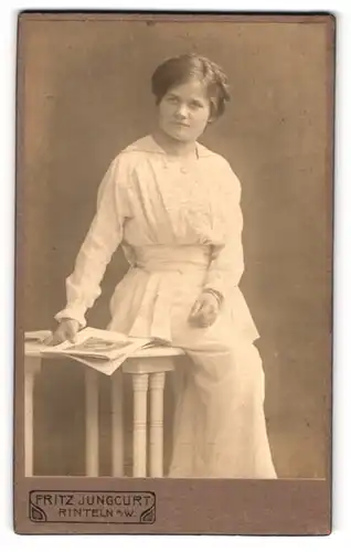 Fotografie Fritz Jungcurt, Rinteln, Portrait bürgerliche Dame mit Zeitung auf Tisch sitzend