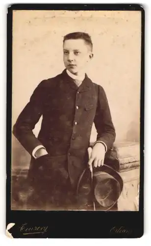 Fotografie Touzery, Orléans, Portrait junger Mann im Anzug mit Hut an Sockel gelehnt
