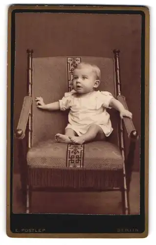 Fotografie E. Postlep, Berlin, Baby im weissen Nachthemd auf einem Sessel