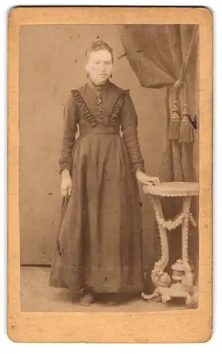 Fotografie Reischig, St. Johann Saarbrücken, Frau im Kleid mit Hand auf einem Beistelltisch