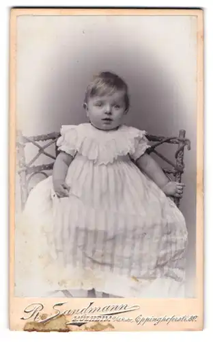 Fotografie R. Sandmann, Mülheim a / Ruhr, Portrait niedliches Kleinkind im hübschen Kleid auf Stuhl sitzend