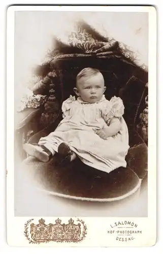 Fotografie L. Salomon, Dessau, Portrait niedliches Kleinkind im hübschen Kleid auf Stuhl sitzend