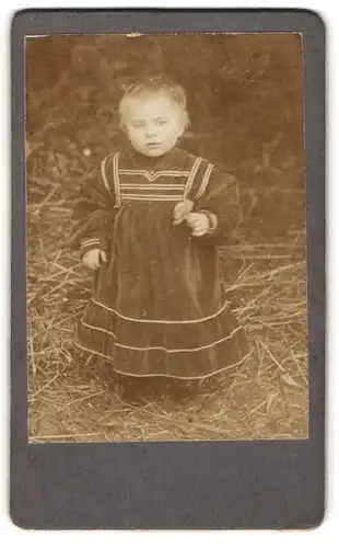 Fotografie unbekannter Fotograf und Ort, Portrait süsses kleines Mädchen im Stroh stehend