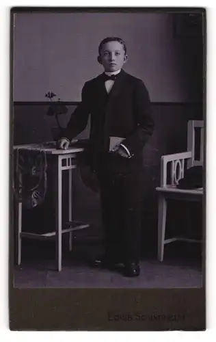Fotografie Louis Schindhelm, Ebersbach i. S., Portrait hübscher Bube mit Buch im Anzug