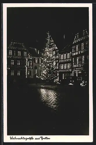 AK Bretten, Strassenpartie mit Geschäft, Denkmal und Tannenbaum bei Nacht, Weihnachtsgruss