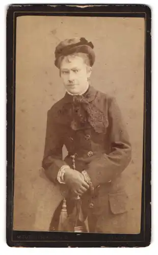 Fotografie M. Guttenberg, Manchester, Portrait junge Frau in herbstlicher Garderobe mit Regenschirm und Hut