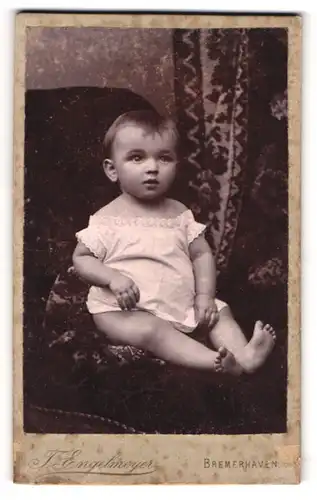 Fotografie T. Engelmeyer, Bremerhaven, Portrait niedliches Kleinkind im weissen Hemd mit nackigen Füssen