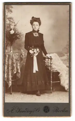 Fotografie A. Jandorf & Co., Berlin, Portrait junge Dame im schwarzen Kleid mit Blumenstrauss