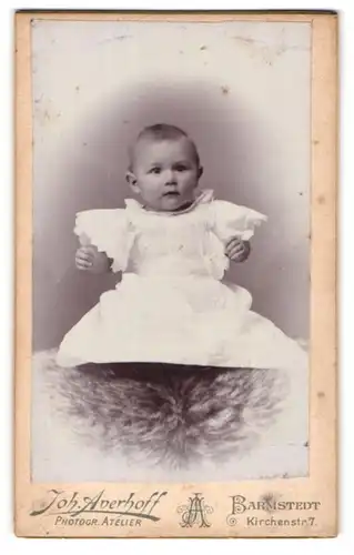 Fotografie Joh. Averhoff, Barmstedt, Portrait niedliches Baby im weissen Hemd auf Fell sitzend