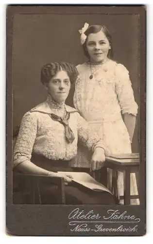Fotografie Friedr. Jähne, Neuss-Grevenbroich, Portrait zwei junge Damen in hübscher Kleidung mit Zeitung
