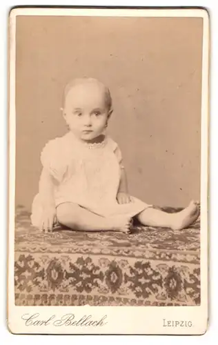 Fotografie Carl Bellach, Leipzig, Portrait kleines Mädchen im weissen Hemd auf Tisch sitzend