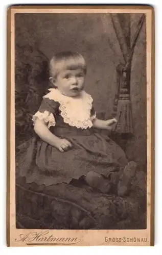 Fotografie A. Hartmann, Gross-Schönau, Portrait niedliches Kleinkind im hübschen Kleid auf Sessel sitzend