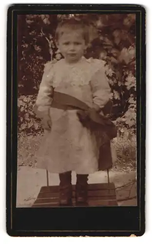Fotografie unbekannter Fotograf und Ort, Portrait Kleinkind in festlicher Kleidung in Garten