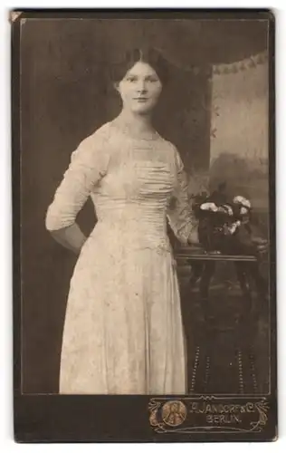Fotografie A. Jandorf & Co., Berlin, Portrait junge Dame in hübscher Kleidung an Tisch gelehnt