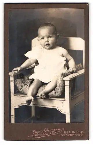 Fotografie Carl Neumann, Berlin-O, Portrait niedliches Kleinkind im weissen Hemd auf Stuhl sitzend