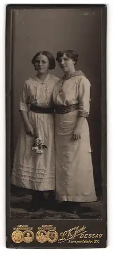 Fotografie L. K. Jué, Dessau, Portrait von zwei jungen Damen in hübschen Kleidern mit Blumen