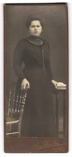 Fotografie H. Schulze, Bautzen, Portrait bürgerliche Dame im schwarzen Kleid an Stuhl gelehnt