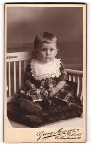 Fotografie Georg Maurer, Halle a / S., Portrait niedliches Kleinkind im karierten Kleid auf Kissen sitzend