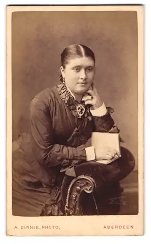Fotografie A. Dinnie, Aberdeen, Portrait bürgerliche Dame mit Buch auf Sessel sitzend