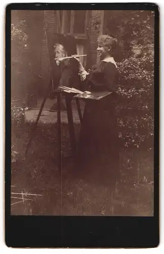 Fotografie unbekannter Fotograf und Ort, Künstlerin / Portrait-Malerin im Garten an Staffelei beim malen eines Portraits