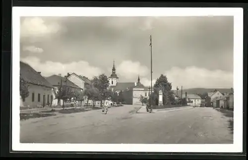 AK Dedice u Vyskova, Einwohnerin in Strasse mit Kirchturm im Hintergrund