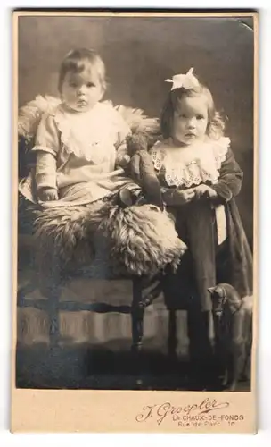 Fotografie J. Groepler, La Chaux-de-Fonds, Portrait süsses Kleinkind im hübschen Kleid mit Teddy und Mädchen
