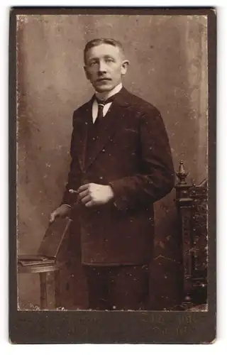 Fotografie N. D. Hellbach, Dingelstädt, Portrait bürgerlicher Herr mit Zigarre und Buch an Tisch gelehnt
