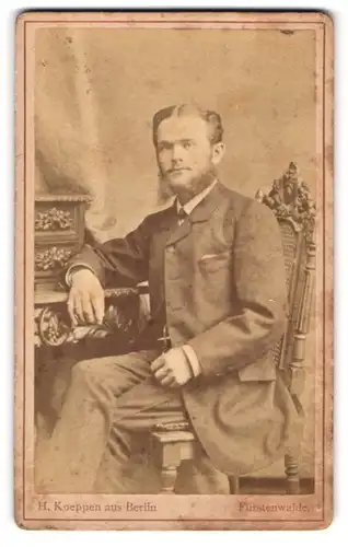 Fotografie H. Koeppen, Berlin, Portrait junger Mann mit modischem Vollbart am Sekretär sitzend