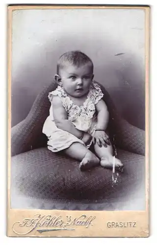 Fotografie F.J. Köhler, Graslitz, Portrait niedliches Baby im Hemdchen auf einem Sessel sitzend