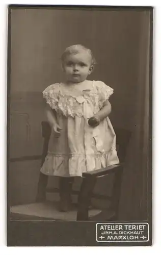 Fotografie A. Dickhaut, Marxloh, Kleinkind stehend im weissen Kleid auf einem Stuhl