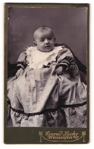 Fotografie Conrad Lucke, Weissenfels a. Saale, Portrait niedliches Baby im karierten Kleid