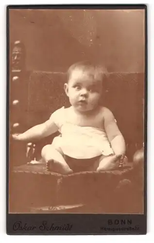 Fotografie Oskar Schmidt, Bonn, Portrait niedliches Baby im weissen Hemd mit nackigen Füssen