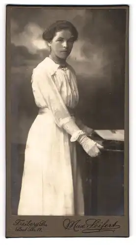Fotografie Max seifert, Freiberg / S., Portrait weiss gekleidete Dame mit Handschuhen am Tisch