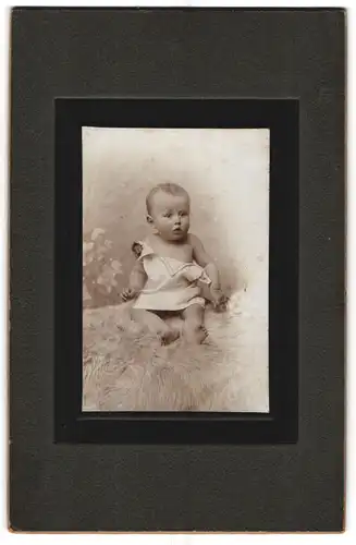 Fotografie unbekannter Fotograf und Ort, Portrait niedliches Baby im weissen Hemd auf Fell sitzend