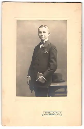 Fotografie Fritz Juhl, Naumburg a / S., Portrait junger Mann im Anzug mit Fliege und Buch