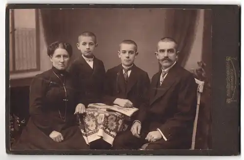 Fotografie Germania, Chemnitz, Portrait bürgerliches Paar und zwei Jungen mit Zeitung am Tisch