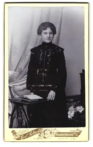 Fotografie Paul Petzold, Brandenburg a / H., Portrait junge Dame im hübschen Kleid mit Buch am Tisch