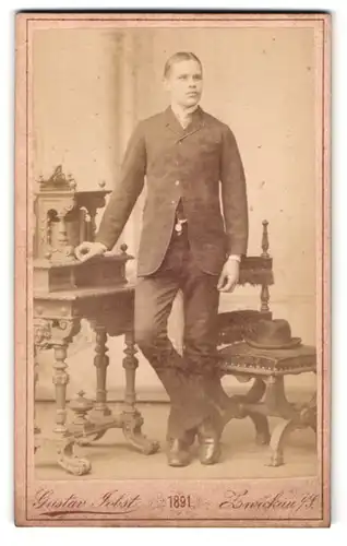 Fotografie Gustav Jobst, Zwickau, Portrait modisch gekleideter Herr an Schreibtisch gelehnt