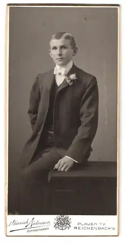 Fotografie Heinrich Axtmann, Plauen i. V., Portrait junger Mann im Anzug mit Fliege an Tisch gelehnt