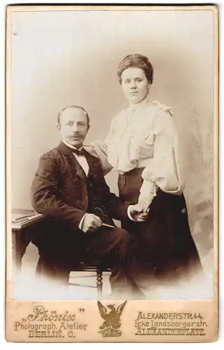 Fotografie Atelier Phönix, Berlin-C, Portrait bürgerliches Paar mit Büchlein sich an der Hand haltend