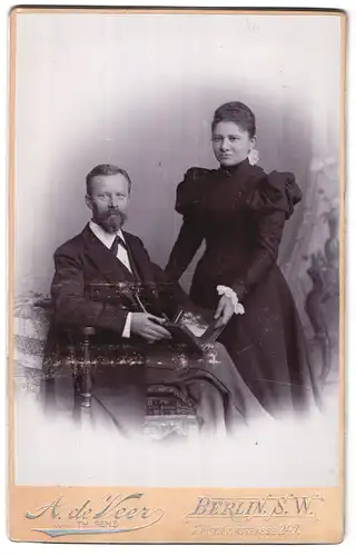 Fotografie A. de Veer, Berlin-SW, Portrait bürgerliches Paar in eleganter Kleidung mit Foto