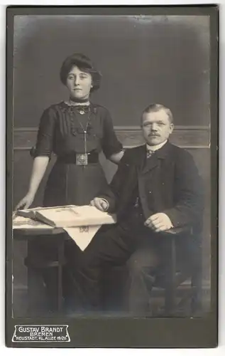 Fotografie Gustav Brandt, Bremen, Portrait bürgerliches Paar mit Buch am Tisch