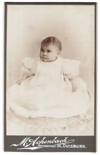 Fotografie M. Achenbach, Duisburg, Portrait niedliches Kleinkind im weissen Kleid mit Halsekette