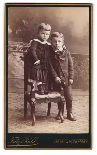 Fotografie Fritz Rühl, Landau, Portrait Kinderpaar in hübscher Kleidung am Stuhl