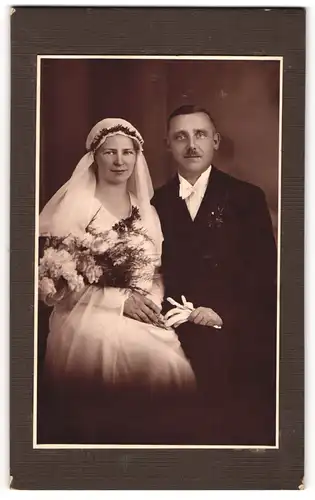 Fotografie unbekannter Fotograf und Ort, Eheleute im Hochzeitskleid und Anzug mit Brautstrauss