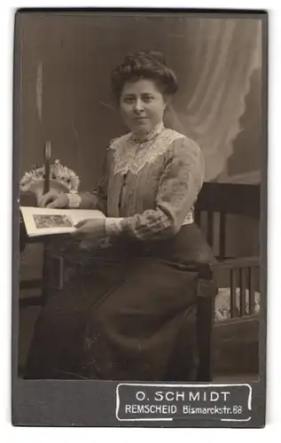 Fotografie O. Schmidt, Remscheid, Dame in spitzebesetztem Kleid bei Tisch